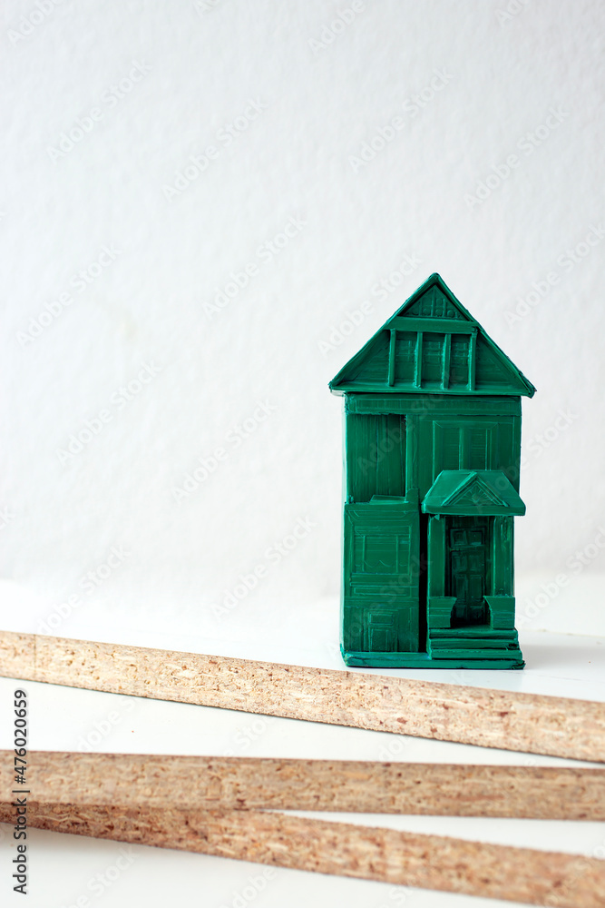 white chipboards edges and a green miniature house.