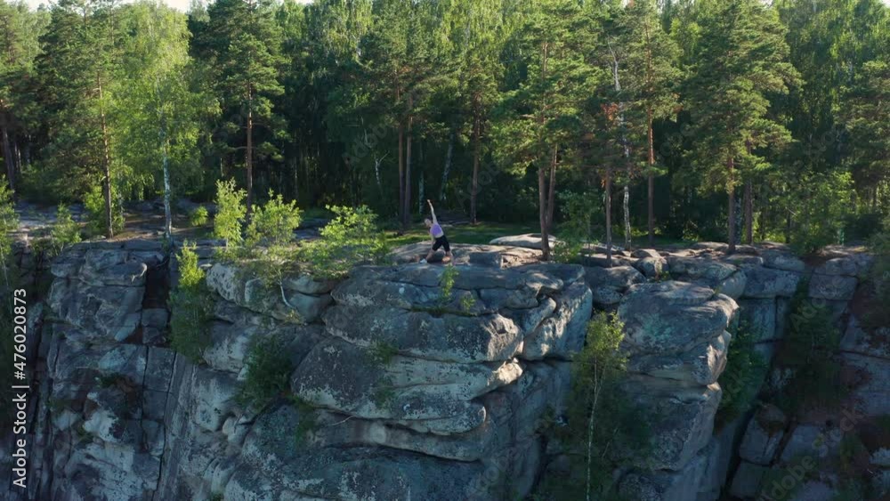 Aerial view of a girl doing fitness and yoga on the edge of a cliff Aerial view of a girl doing fitness and yoga on the edge of a cliff