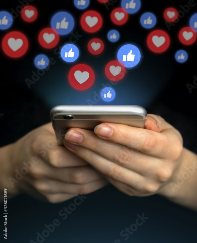 Social media concept. Hands using smartphone with like notification icons. Social networking, black background photo