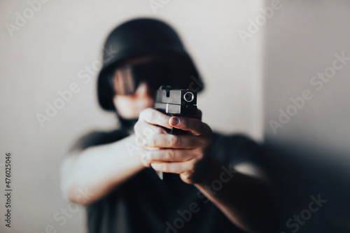 A man in a black helmet stands with a gun in his hands and takes aim. Crime. Army and police.