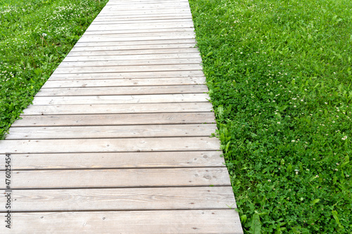 the path in the park is made of wooden boards, beautiful paths in the garden are made of wooden bars and boards, green grass