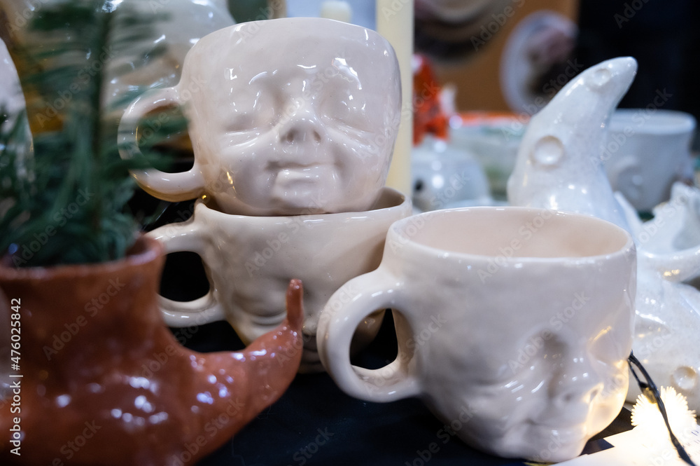 Handmade ceramic souvenirs. Clay cups with a human face.