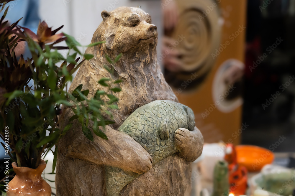 Handmade clay figurine of a brown Siberian bear with a fish in its paws.