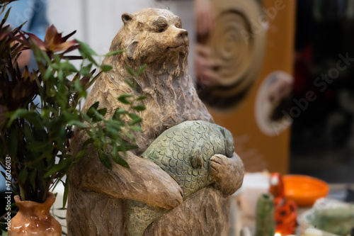 Obraz na płótnie Handmade clay figurine of a brown Siberian bear with a fish in its paws. w salonie