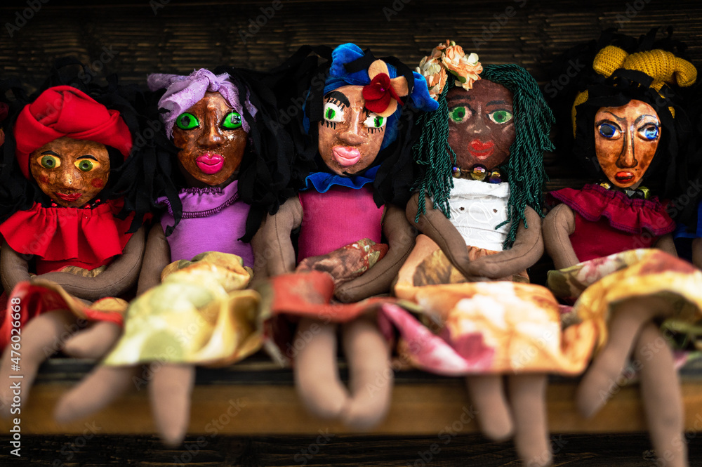 A row of handmade dark-skinned dolls. Baby toys in the form of girls.