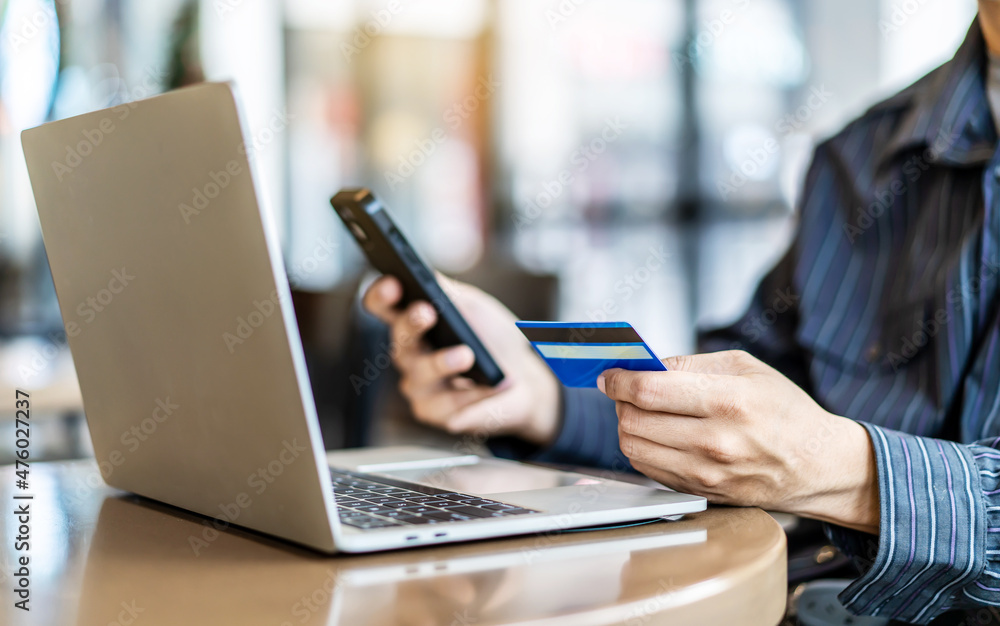 Businessman in casual shirt paying with credit card online while making orders via the Internet.Man's hands holding a credit card and using smart phone for online shopping. Selective focus Businessman in casual shirt paying with credit card online while making orders via the Internet.Man's hands holding a credit card and using smart phone for online shopping. Selective focus
