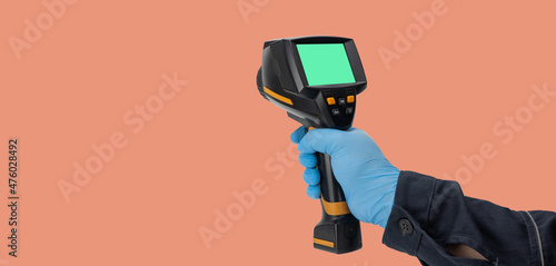 man in rubber gloves holds a thermographic camera. device for monitoring the temperature distribution of the surface under study. thermal imager in hand. Infrared thermography