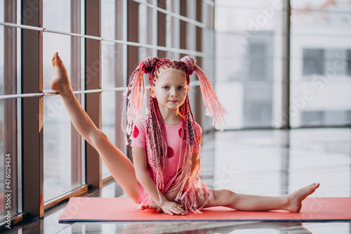 Foto Cute little girl doing gymnastics on mat in studio