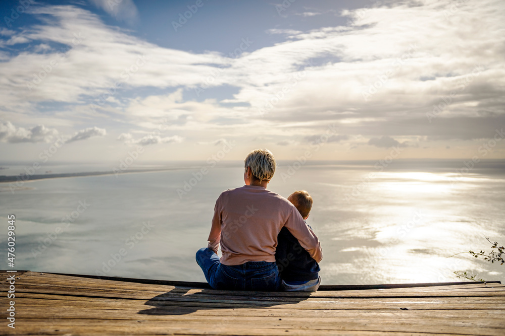 Mother and 3 years old son hugging each other and enjoying the beautiful ocean views