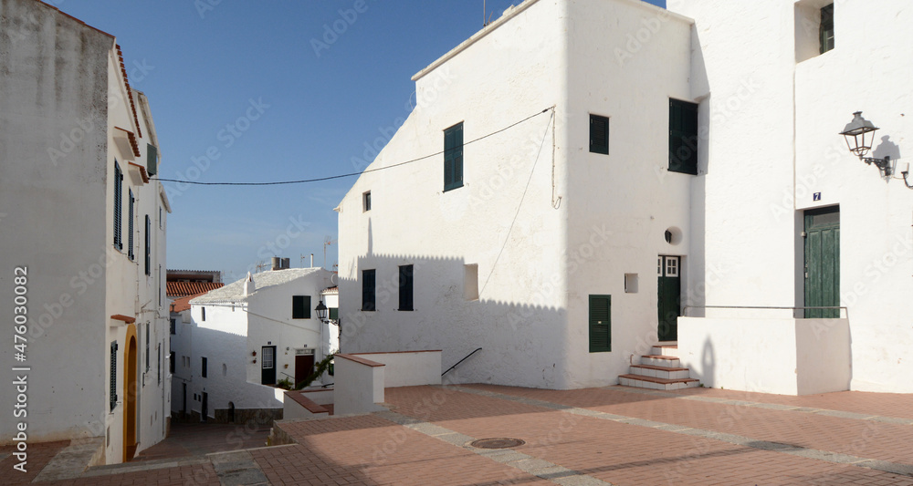 Houses with the sun. Menorca is one of the Spanish Balearic Islands in the Mediterranean Sea. It is known for the rocky and turquoise beaches and bays called 