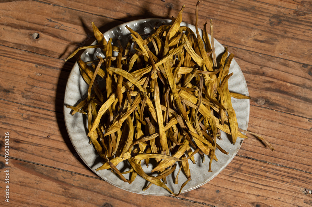 Dried day lily in a container on a wooden countertop