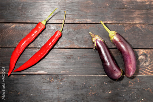 Red chili and eggplant on wood background.