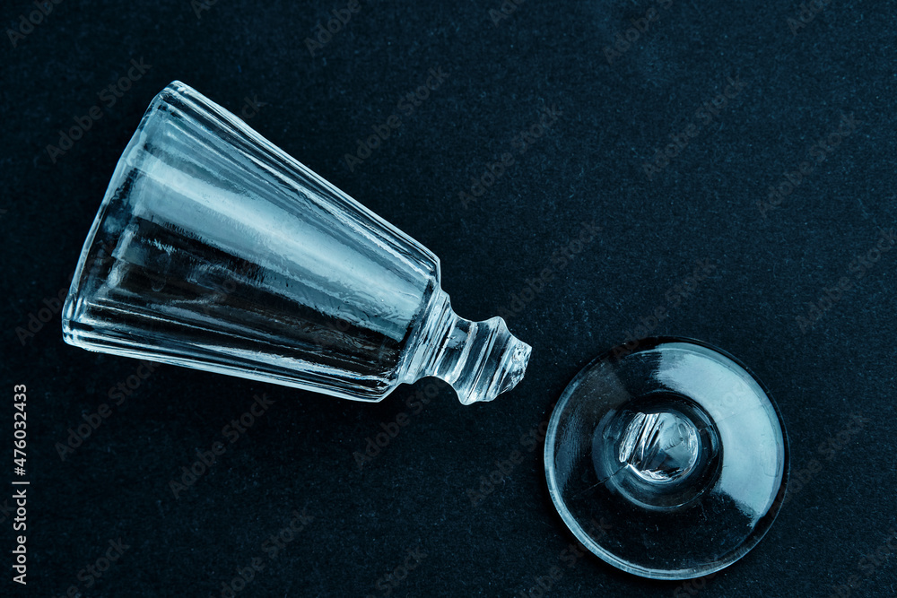 A close-up of a broken small shot glass. Minimal concept of alcoholism problems A close-up of a broken small shot glass. Minimal concept of alcoholism problems