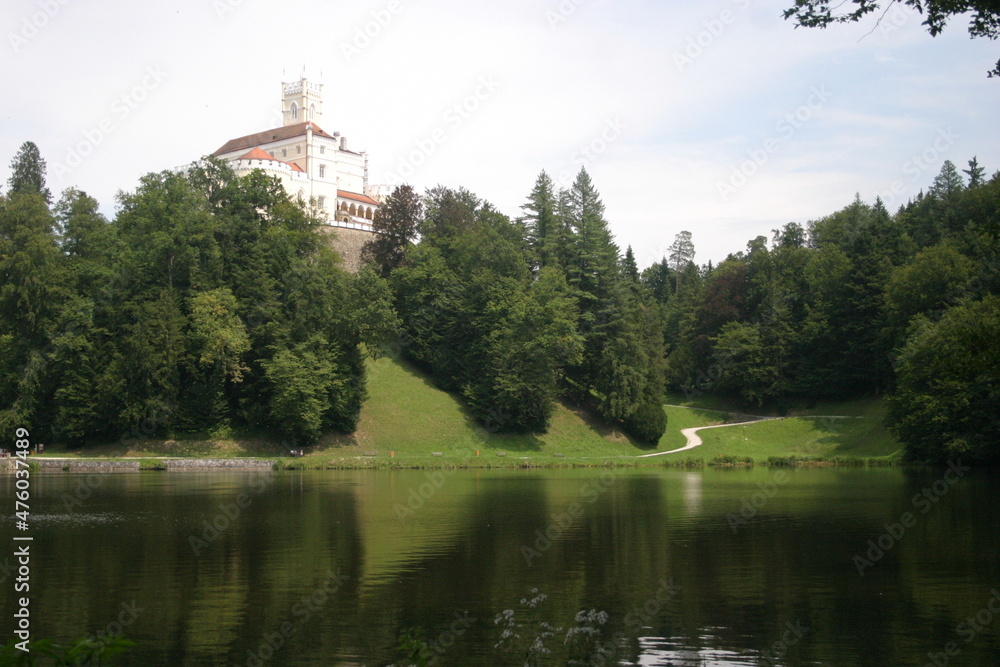 Obraz premium A castle on the hills, decidous forest and a beautiful lake in summer