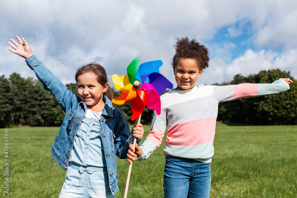 Φωτογραφία childhood, leisure and people concept - happy girls with pinwheel having fun at
