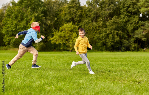 childhood, leisure and people concept - happy boys playing seek and hide game at park