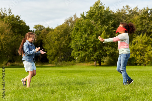 childhood, leisure and people concept - happy girls playing tag game and running at park