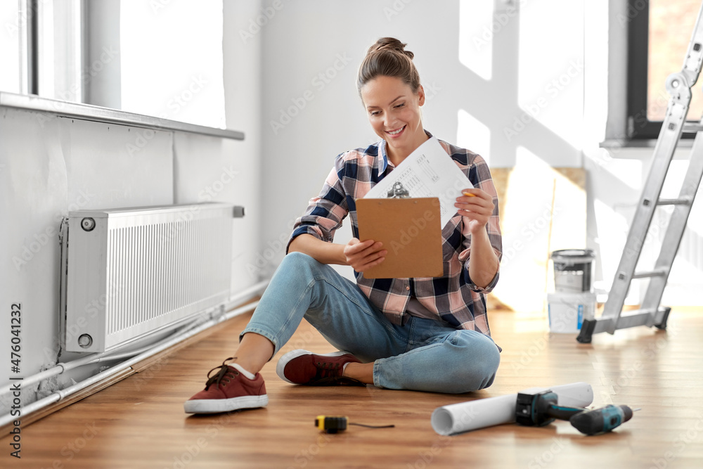 Φωτογραφία repair, people and real estate concept - woman with clipboard sitting on floor a