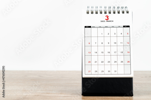 March 2022 desk calendar on wooden table.