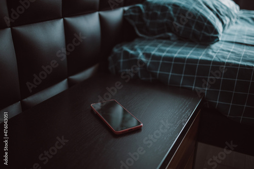 Photography Smartphone on nightstand near bed in hotel room. Modern interior