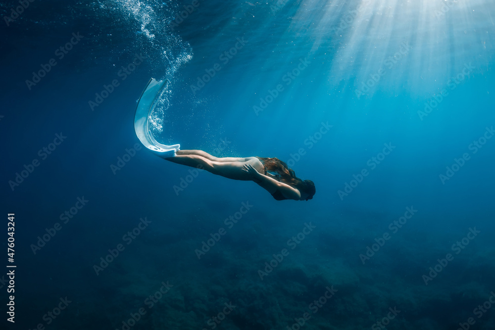 Freediver woman in bikini with fins dive underwater in deep blue sea.