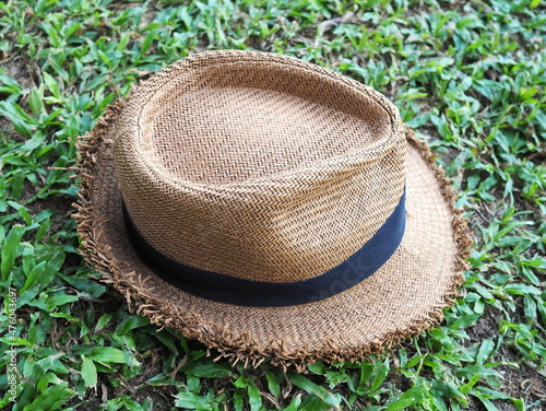 Artificial brown Panama Hat from natural materials laid Surrounded by a black bow on the green grass in the garden. Panama Hat as a fabric analogue of a straw hat for the beach and nature
