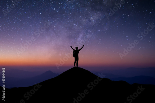 Young traveler with backpack standing and open both arm watched night sky view  star and milky way alone on top of the mountain. He enjoyed traveling and was successful when he reached the summit.