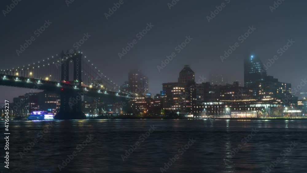 Timelapse of the high buildings of Brooklyn district, illuminated Brooklyn bridge that crosses the East River in New York City, USA. Night. Touristic ferries sail along the river under the bridge Timelapse of the high buildings of Brooklyn district, illuminated Brooklyn bridge that crosses the East River in New York City, USA. Night. Touristic ferries sail along the river under the bridge