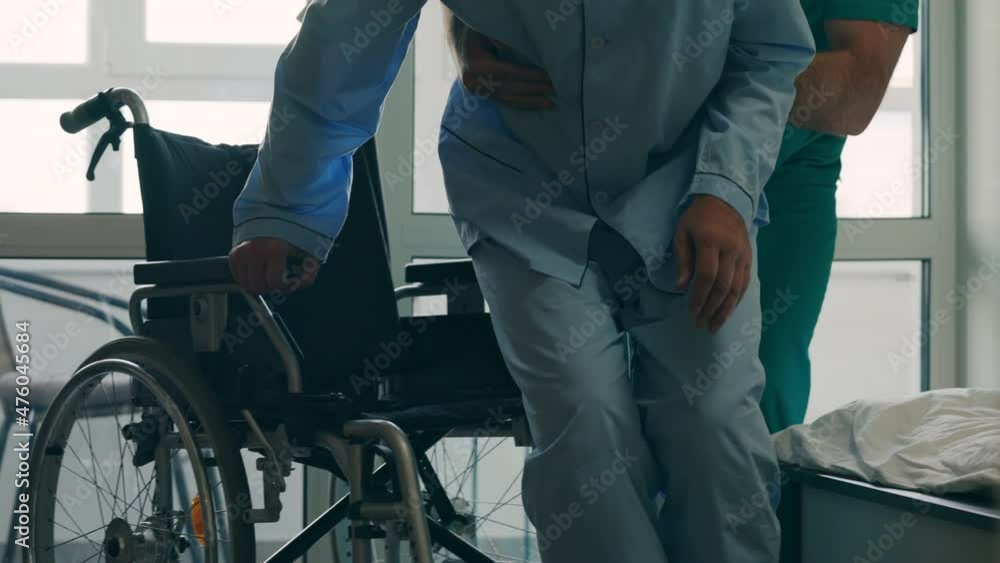 Male nurse taking care of weak elderly patient with disability, retirement home Male nurse taking care of weak elderly patient with disability, retirement home