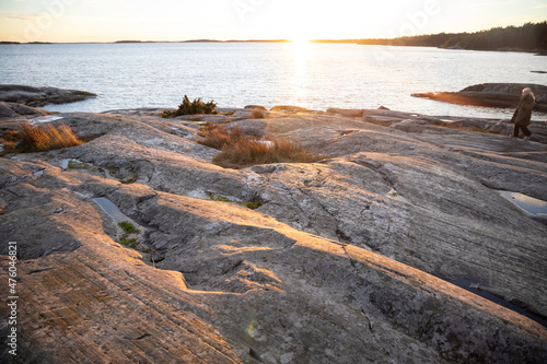 People walking on a rocky shore in Bjorno nature reserve at Baltic sea. Beautiful natural Scandinavian landscape on Sunny late autumn or winter day in Sweden, Stockholm archipelago 2021.12.17