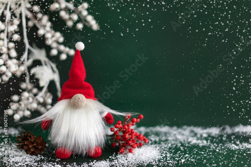 Scandinavian Christmas gnome with winter berry and pine on dark green background. New year greeting card design photo