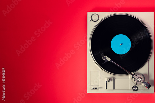 Gramophone with a vinyl record on a red table, top view and copy space,split toning for old style.
