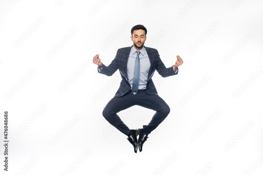 businessman in suit levitating and meditating on white. businessman in suit levitating and meditating on white.