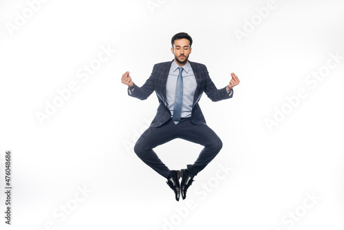 businessman in suit levitating and meditating on white.