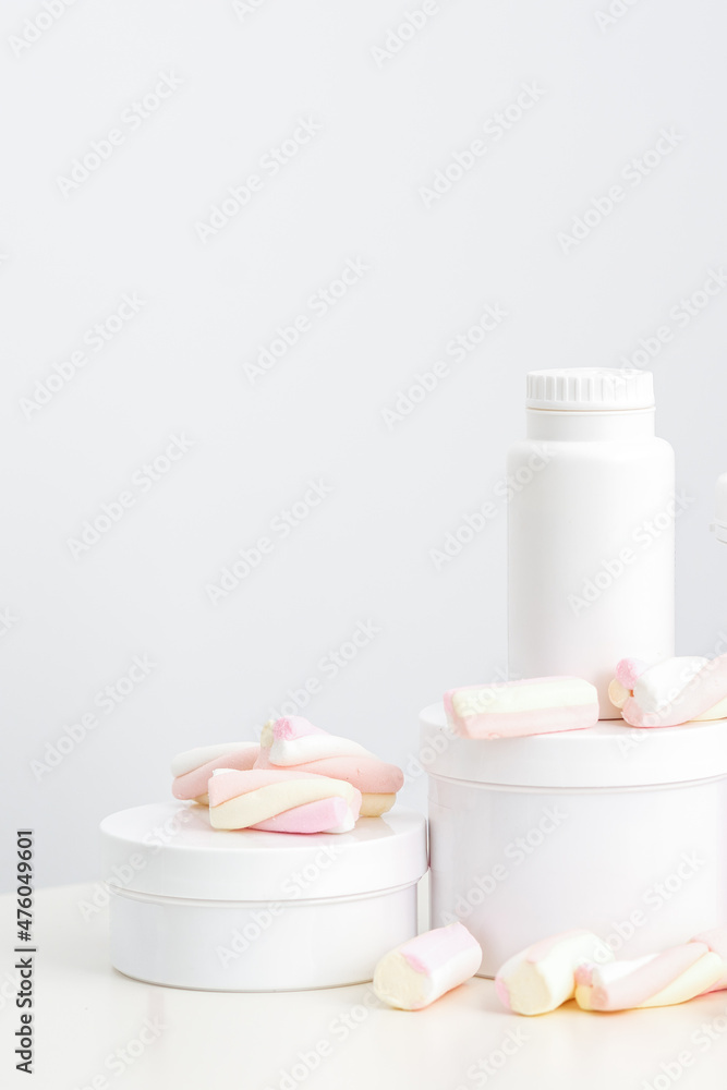 Cosmetic skincare packaging. Beauty product on white background. White jars with marshmallows on the white table Cosmetic skincare packaging. Beauty product on white background. White jars with marshmallows on the white table