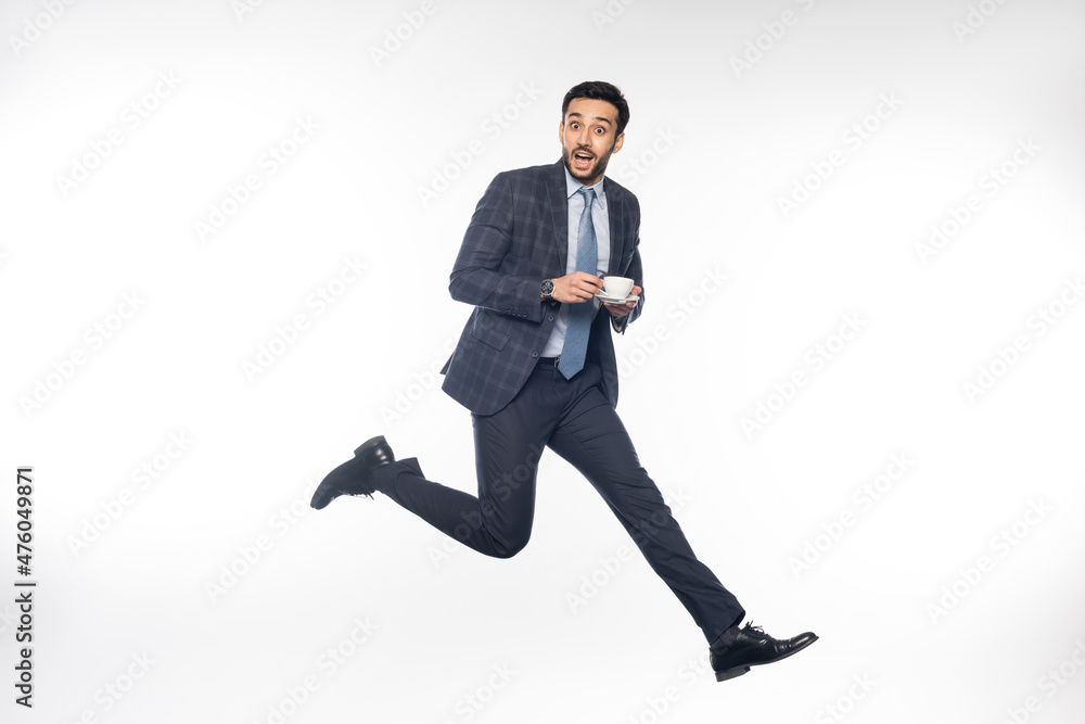 excited businessman in suit jumping with cup of coffee on white. excited businessman in suit jumping with cup of coffee on white.