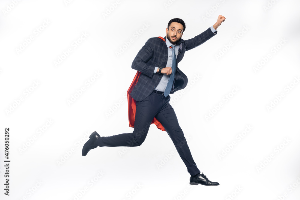 businessman in suit and superhero cape levitating on white.