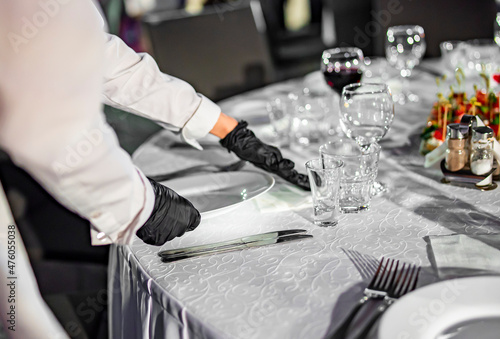 Waitress hand in gloves puts the plate, table setting © pavel siamionov