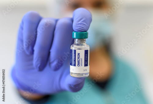 Close-up photo of medical worker holding covid vaccine vial with omicron variant text on label photo