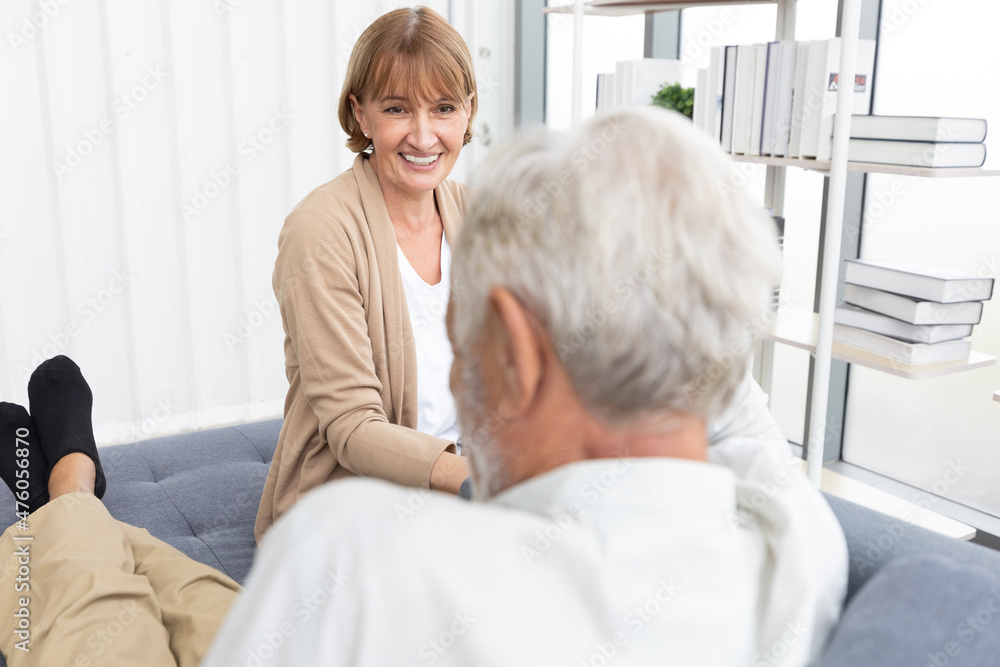 Obraz premium senior woman talking and smiling with senior man on sofa