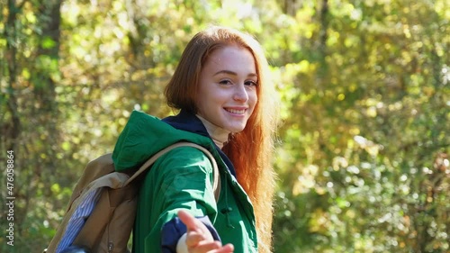 Young woman inviting to walk with her through forest photo