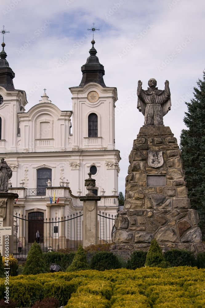 Obraz premium Monument next to the church surrounded by trees and alleys.