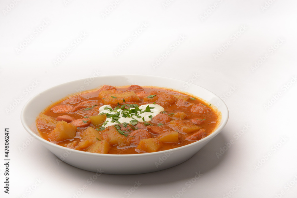 homemade dish so-called Erdapfelgulsch on a white plate with white background homemade dish so-called Erdapfelgulsch on a white plate with white background