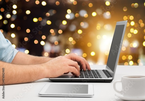 Female hands on the laptop with gifts and blurred bokeh lights. Christmas shopping online, sales and discounts promotions