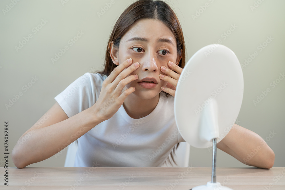 Bored, insomnia asian young woman, girl looking at mirror, without makeup, touch under eyes with problem of dark circles, puffiness, swollen or wrinkles on face. Sleepless, sleepy people, copy space Bored, insomnia asian young woman, girl looking at mirror, without makeup, touch under eyes with problem of dark circles, puffiness, swollen or wrinkles on face. Sleepless, sleepy people, copy space