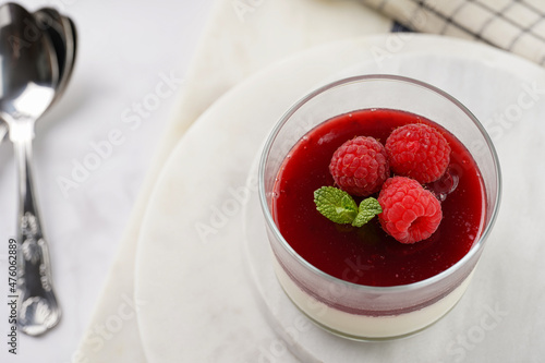 Italian dairy dessert panna cotta with raspberry jam and fresh raspberries on marble board