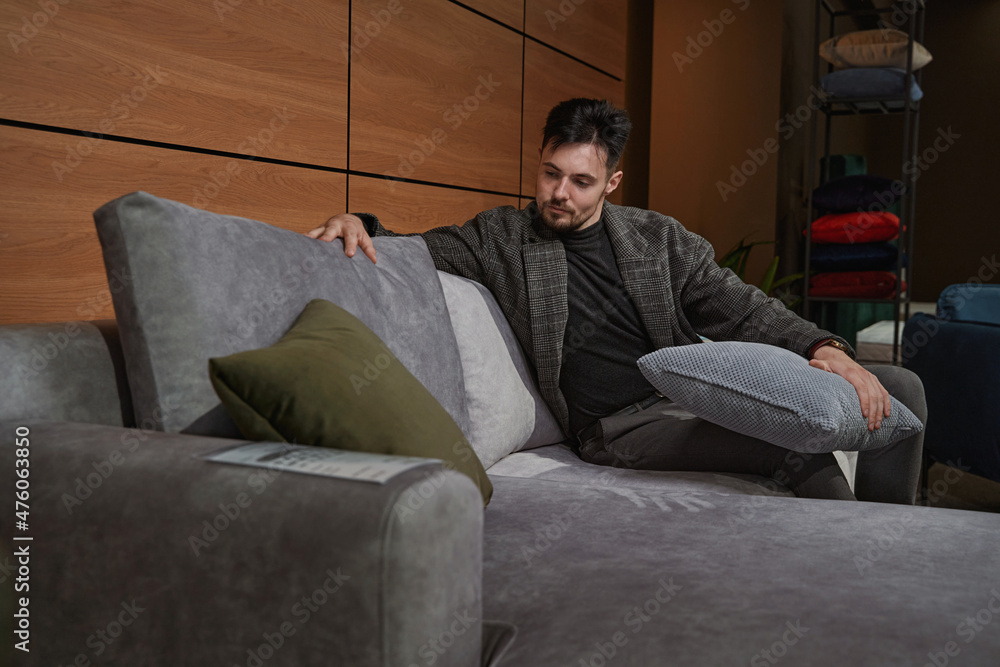 Concentrated guy choosing new pillows for couch