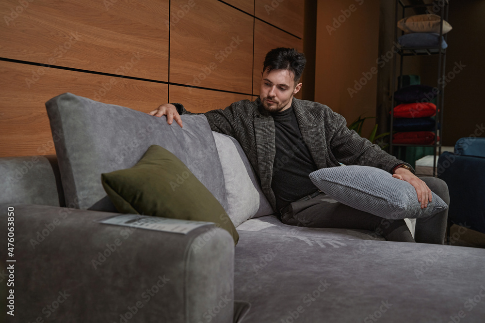 Concentrated guy choosing new pillows for couch Concentrated guy choosing new pillows for couch