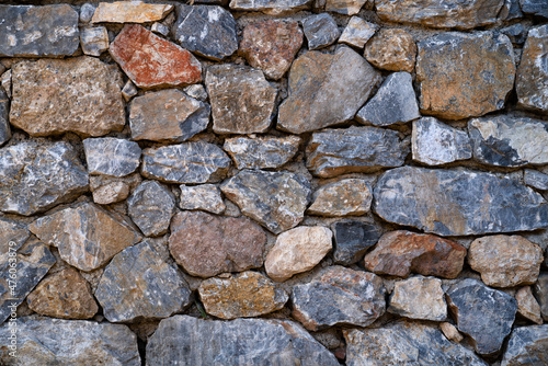 Background texture of masonry wall made of natural multicolored stones.