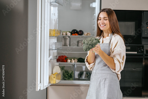 Young housewife standing near the fridge in the kitchen photo